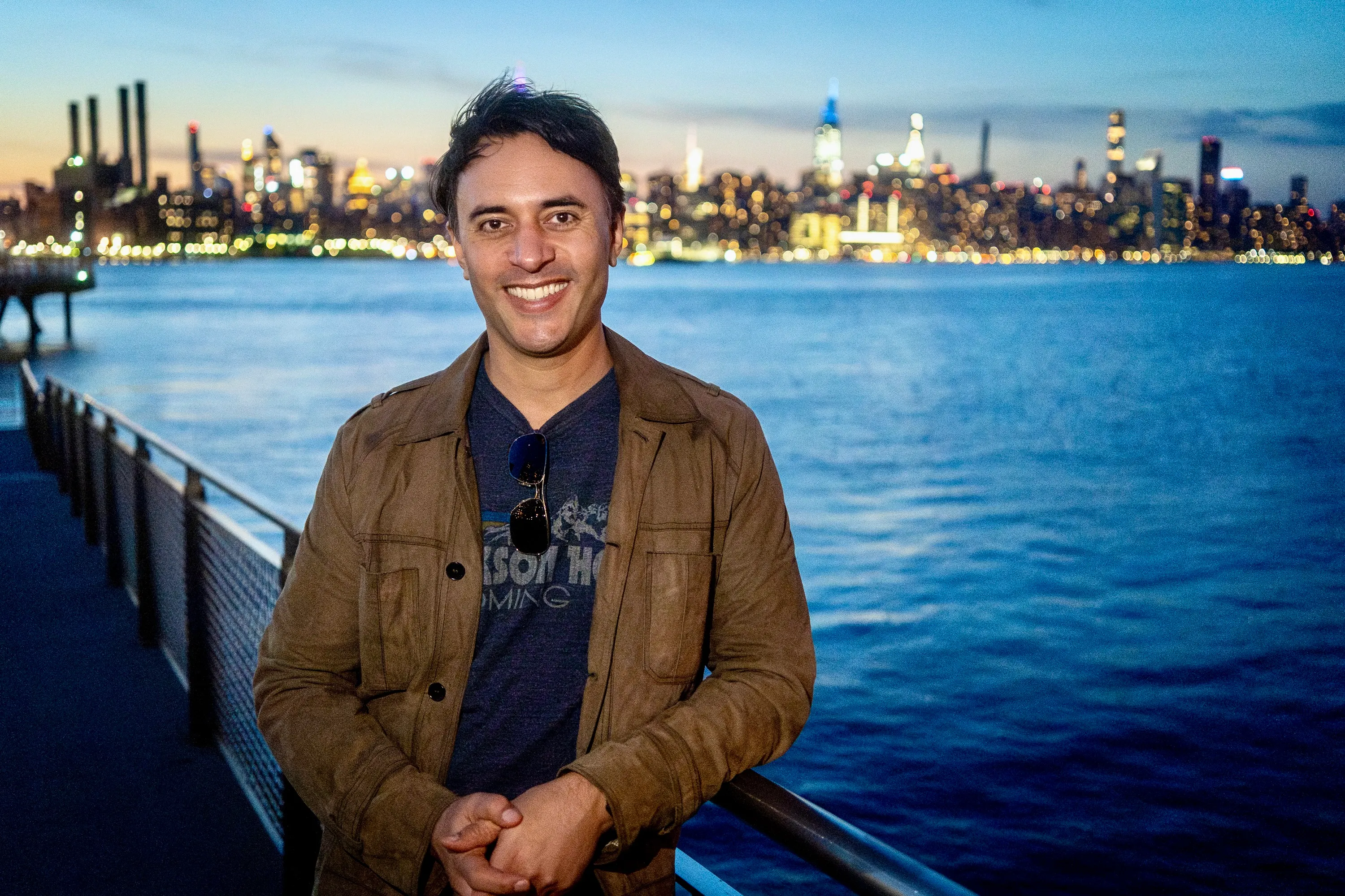Jay Dixit beside the East River with the Manhattan skyline behind him